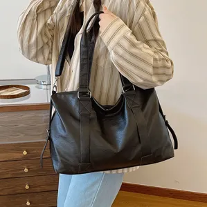 Detail view of large capacity black PU leather tote bag with double handles and shoulder strap.