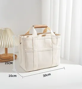 Close-up detail of canvas diaper tote bag featuring multiple exterior pockets and handles.