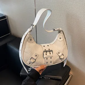 White crocodile pattern crescent motorcycle shoulder bag, detailing view with metal studs and buckles.