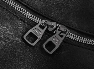 Close-up detail of black leather travel bag metal zipper and double puller hardware.