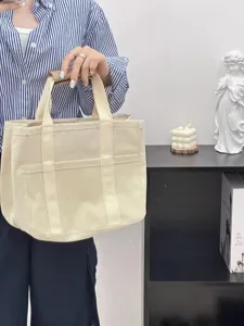 Detailed view of casual canvas diaper tote bag with multiple front pockets for daily mother use.