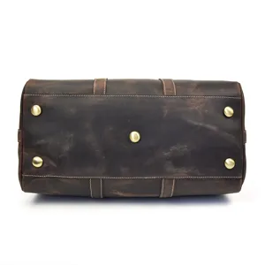 Détail du fond de sac de voyage vintage en cuir avec rivets métalliques et coutures.
