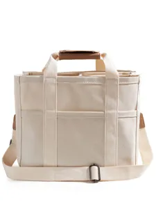 Beige canvas diaper bag with multiple compartments, top handles and adjustable shoulder strap.