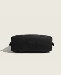 Detailed bottom view of a black leather travel duffel bag, showing reinforced stitching.