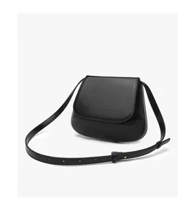 Close-up detail of the black leather saddle bag showing texture, strap, and fine stitching.