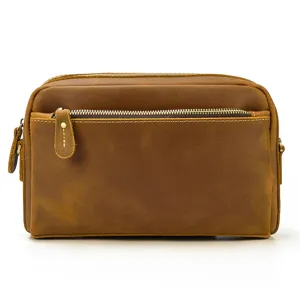 Détail de pochette en cuir marron avec poche zippée lisse et texture de couture fine.