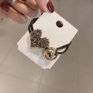 Detailed view of the sparkling rhinestone heart hair rope and golden ball accessory.