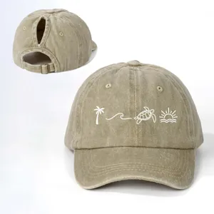 Detail der khakifarbenen Pferdeschwanz-Baseballkappe mit sommerlicher Strandstickerei.