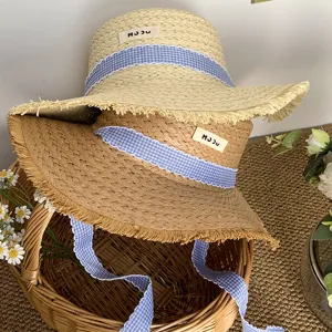 Chapeau de paille plat français à ruban et bord frangé pour les vacances d'été au bord de la mer.
