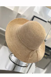 Detail view of the handmade woven raffia sun hat, featuring a wide brim and delicate braided string.