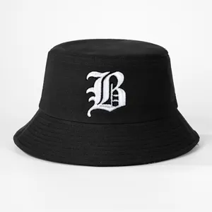 Detailed close-up of a black cotton bucket hat featuring white gothic letter embroidery.