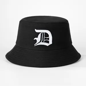 Close-up detail of a classic black bucket hat featuring white gothic letter embroidery.