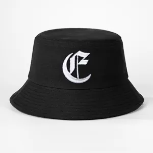 Close-up detail view of the black bucket hat showcasing the white Gothic letter embroidery.