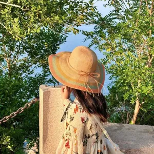 Chapeau de paille pour femme a large bord avec rayures colorees et noeud pour vacances.