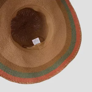 Vue détaillée de l'intérieur du chapeau de paille rayé, montrant le tressage et le bord.