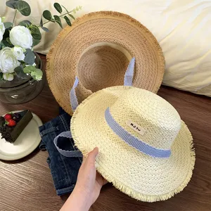 Chapeau de paille plat français avec franges et ruban à carreaux, idéal pour la plage d'été.