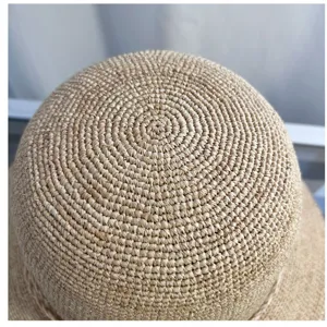 Close-up detail of the hand-woven raffia straw hat crown, showing delicate texture craftsmanship.