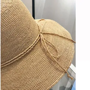 Handmade raffia sun hat detail, wide brim straw beach hat with woven bow decoration for summer.