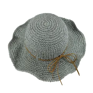 Gros plan détaillé du chapeau de paille gris tissé avec un élégant nœud en cuir.