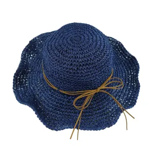 Chapeau de paille tisse bleu marine avec noeud marron, detail de bord ondule pour la plage d'ete.