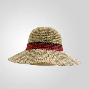 Vue de détail du chapeau de paille fait main avec un motif de bande tissée rouge et noire.