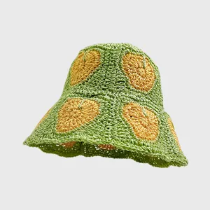 Nahaufnahme des handgemachten grünen Häkel-Strohhutes mit gelbem Herzmuster im Detail.