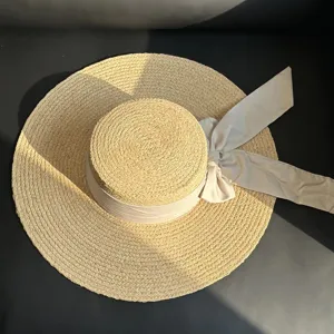 Vue de détail d'un chapeau de paille élégant avec un top plat et un nœud ruban.