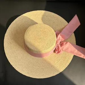 Chapeau de paille plat français avec nœud rose, large bord pour la plage et le soleil en été.
