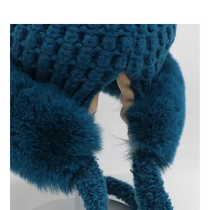 Close-up detail of dark blue plush crochet winter warm earflap beanie hat texture.