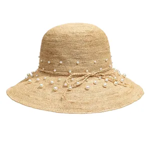 Raffia sun hat detail, handmade woven straw with elegant pearl decorations and bow string for summer beach.