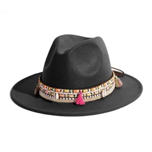 Detail van zwarte fedora hoed met gekleurde geweven band, kwastjes en schelpdecoraties.