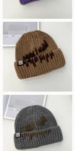 Detailed view of thick warm knit beanie hat with unique embroidery and stylish brim label.