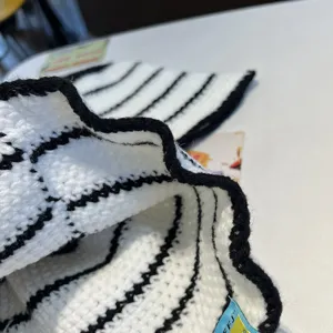 Primo piano sulla texture e sul bordo ondulato di questo cappello da pescatore a maglia.