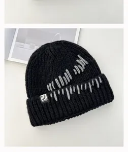 Black knitted beanie hat with unique grey stitching detail and logo label for winter warmth.