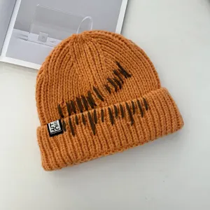 Orange chunky knit beanie for women, warm winter hat with stitched design and stylish tag.