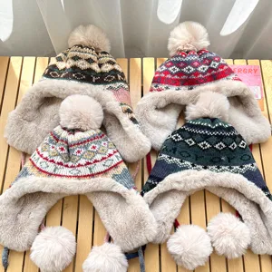 Detailed shot of winter warm knit ushanka hats with fluffy pom poms and jacquard patterns.