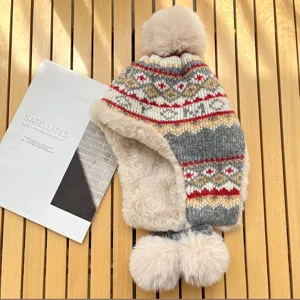 Detailed shot of cozy knit ear-flap winter hat with fluffy pom-poms and warm faux fur lining.
