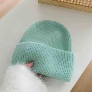 Vue détaillée du bonnet en tricot vert menthe doux, texture duveteuse, bonnet d'hiver chaud.