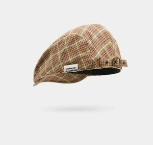 Détail casquette plate à carreaux avec motif vintage, sangle à boucle et étiquette.