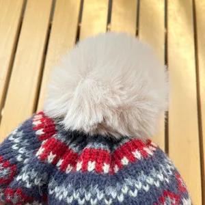 Close-up of winter thick knit beanie with fluffy pom-pom, soft jacquard pattern wool hat.