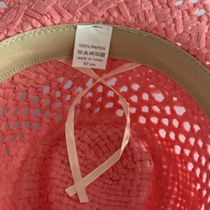 Vue détaillée de l'intérieur du chapeau de paille en papier rose avec étiquette de taille.