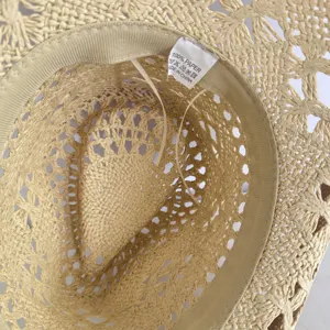 Detailed view of hollow woven straw hat interior showing quality paper material tag and craftsmanship.