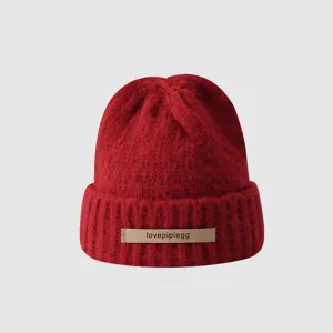 Red knit beanie hat detail view, soft winter wool headwear texture close up display.