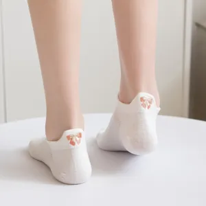 Primo piano di calzini corti bianchi da donna con delicato ricamo a fiocco sul tallone e linguetta