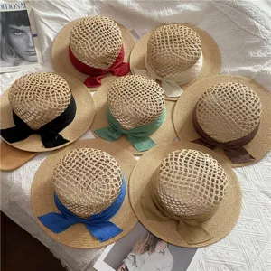 Detail shot of hollow straw hats with colorful ribbon bows, flat top summer beach style.