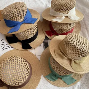 Resort style hollow raffia straw hat with colorful ribbon bow for women beach sun protection.