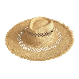 Detailed view of the wide-brim frayed raffia sun hat, showcasing straw weaving and texture.