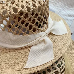 Detailed view of women straw hat with hollow design and elegant ribbon bow for beach vacation.