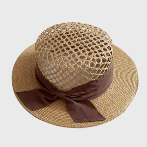 Raffia hollow flat-top straw hat detail, brown ribbon bow, exquisite weaving texture.