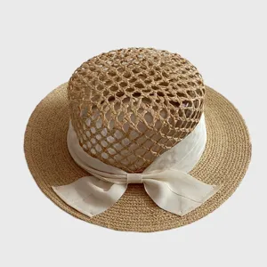 Resort style raffia hollow flat top straw hat with elegant white ribbon bow detail.